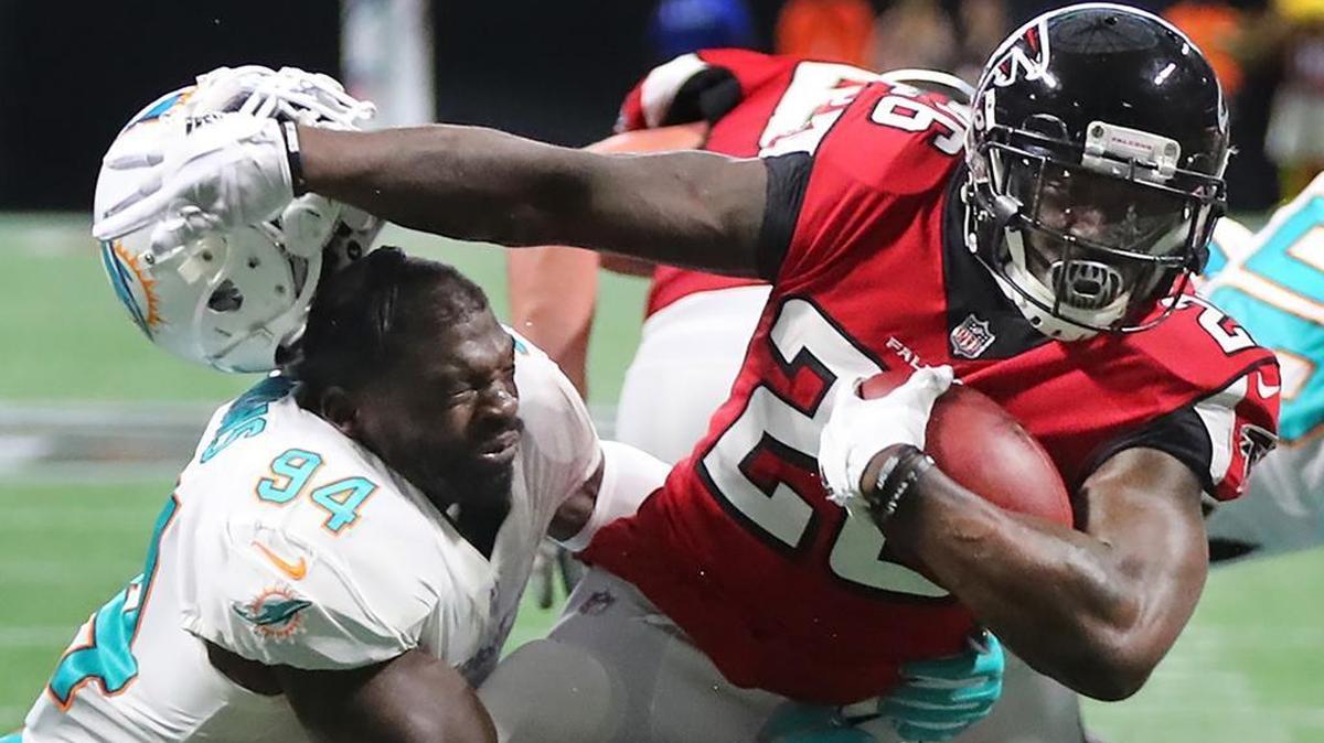Atlanta Falcons running back Tevin Coleman separates Miami Dolphins linebacker Lawrence Timmons from his helmet as he breaks the tackle to run for a touchdown on Oct. 15, 2017.