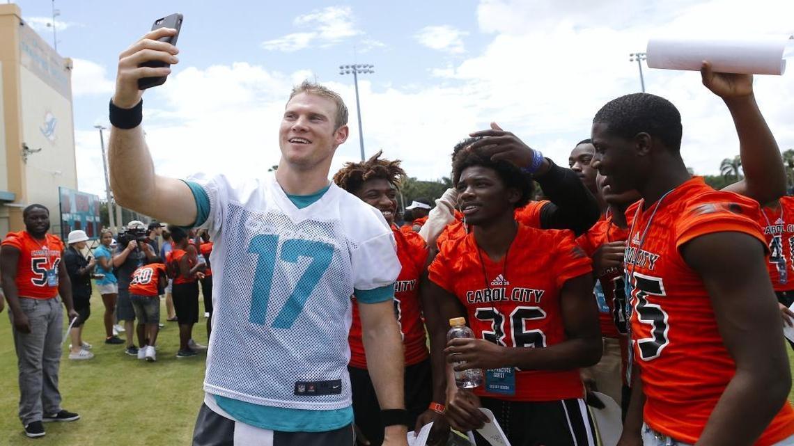 Miami Dolphins quarterback Ryan Tannehill takes a selfie with members of the Miami Carol City Senior High School football team after practice Thursday.