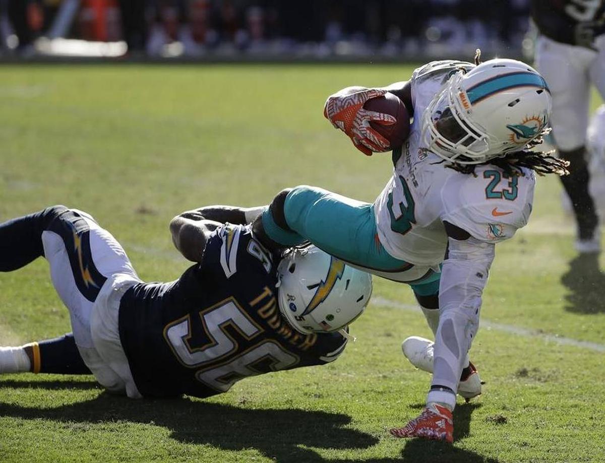 Miami Dolphins running back Jay Ajayi, right, gets tackled by San Diego Chargers inside linebacker Korey Toomer during the first half of an NFL football game in San Diego on Nov. 13, 2016.