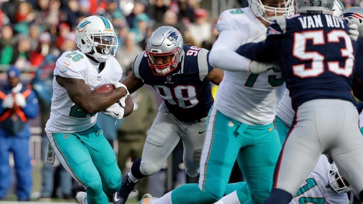 Miami Dolphins running back Damien Williams (26) runs for yardage as he is chased by then-New England Patriots defensive end Trey Flowers (98) and linebacker Kyle Van Noy (53) during the first half of a 2017 game. Williams is now with Kansas City and Flowers with Detroit. Van Noy, still with the Patriots, would be a potential free agent option for Miami.