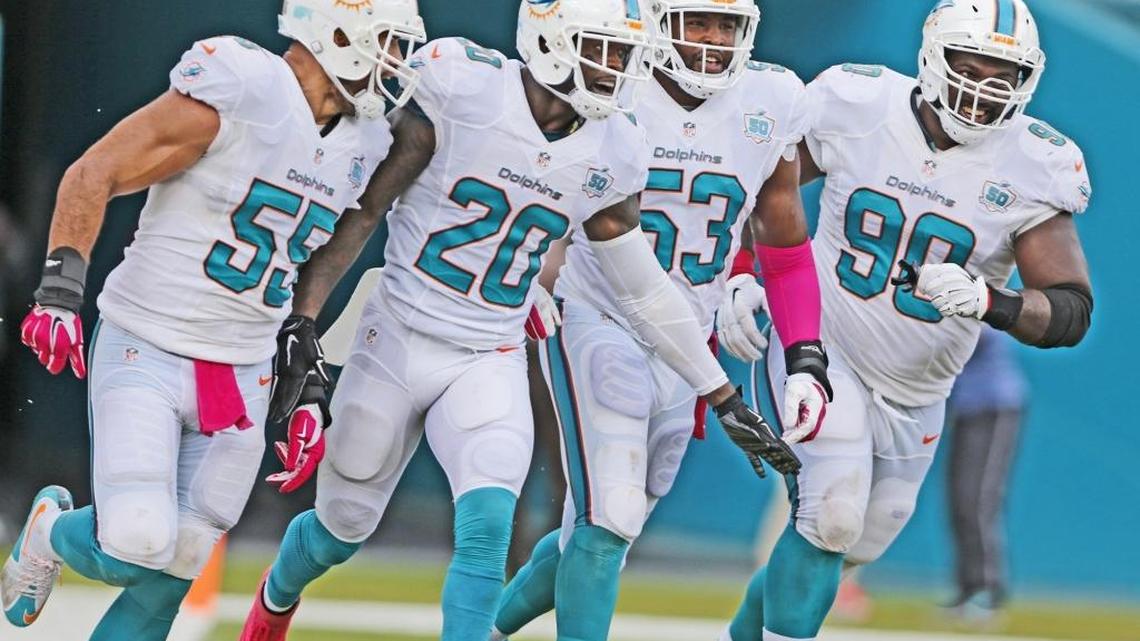 Miami Dolphins safety Reshad Jones (20) celebrates with teammates Koa Misi (55), Jelani Jenkins (53) and Earl Mitchell (90) after Jones scored on an interception return against the Houston Texans at Sun Life Stadium on Sunday, Oct. 25, 2015.