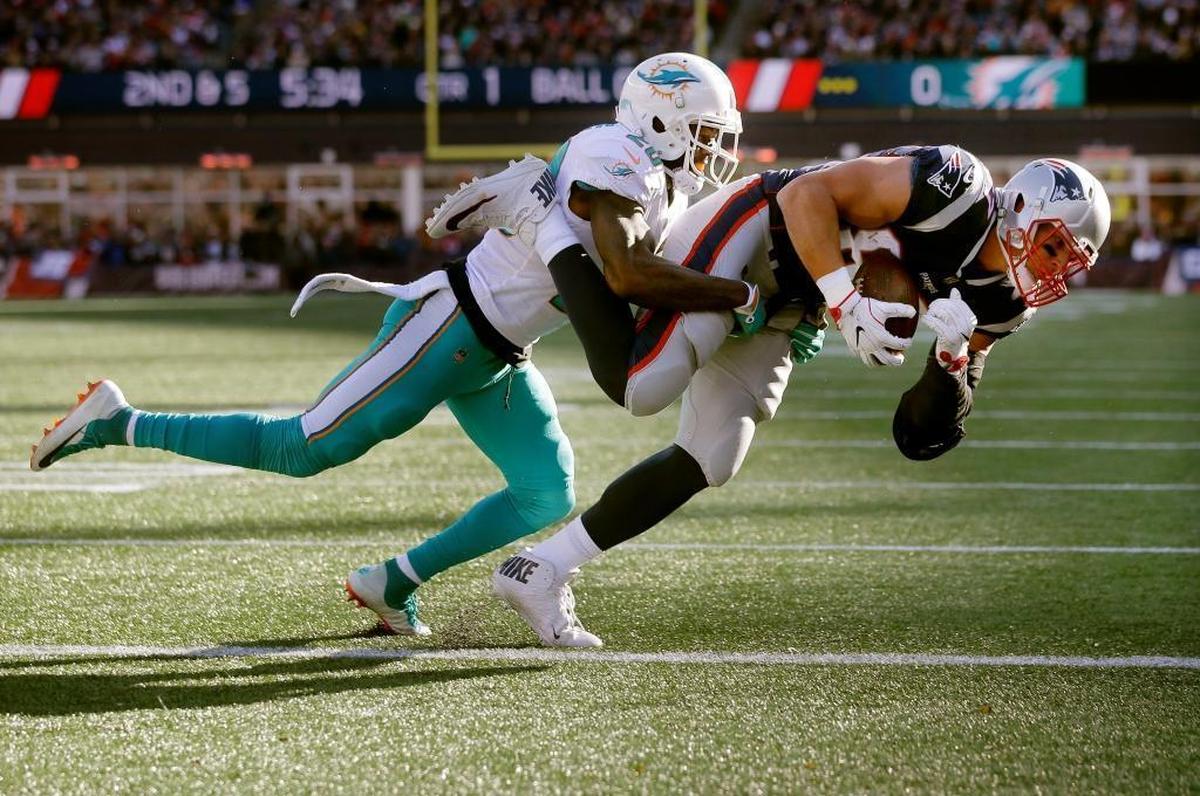 New England Patriots tight end Rob Gronkowski, right, scores a touchdown with Miami Dolphins safety Reshad Jones on his back during the first half of the game on Sunday, Nov. 26, 2017, in Foxborough, Massachusetts.