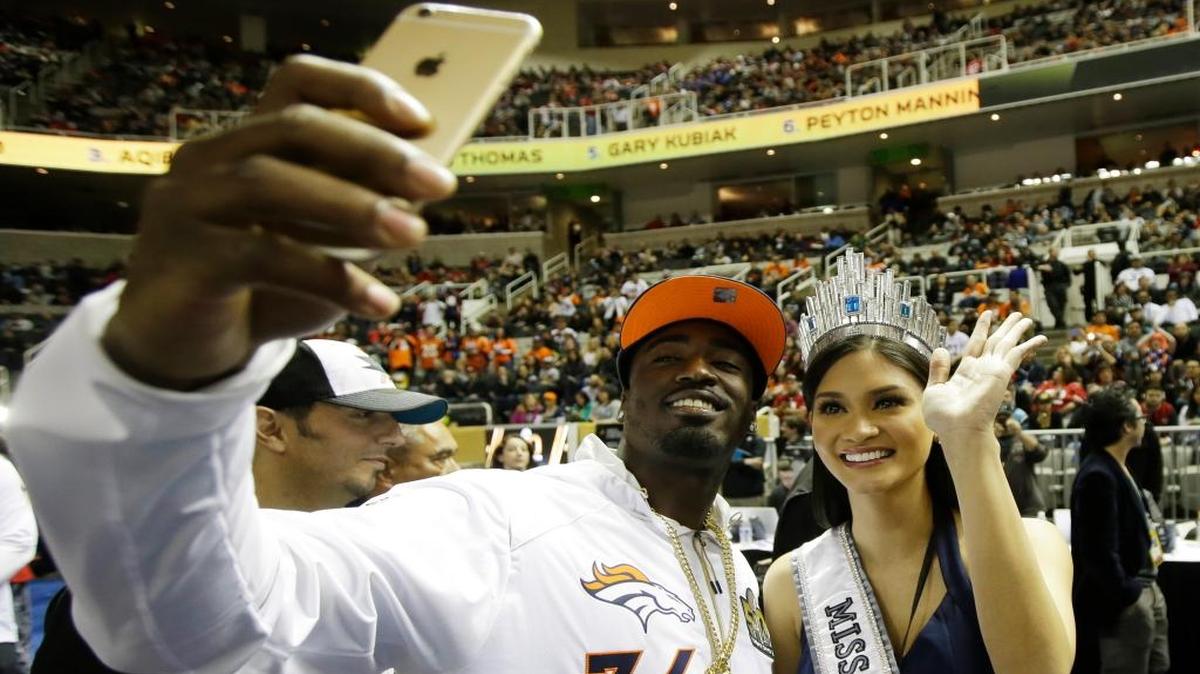 Denver Broncos cornerback Kayvon Webster poses with Miss Universe Pia Alonzo Wurtzbach during Opening Night for the NFL Super Bowl 50 football game Monday, Feb. 1, 2016, in San Jose, Calif.