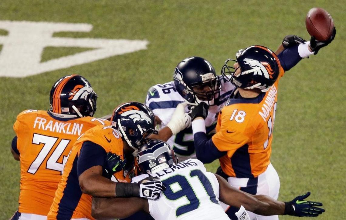 Denver’s Peyton Manning is hit by Seattle’s Cliff Avril (56), a hit that forced a fluttering pass that Malcolm Smith returned for a touchdown during Super Bowl XLVIII.