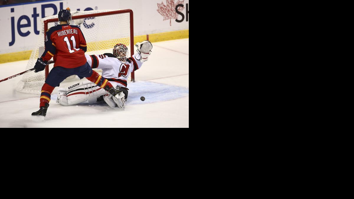 
Florida Panthers' Jonathan Huberdeau (11) applies pressure as New Jersey Devils' goalie Cory Schneider (35) deflects a shot on goal during the first period of a NHL hockey game in Sunrise on Oct. 11, 2014.

