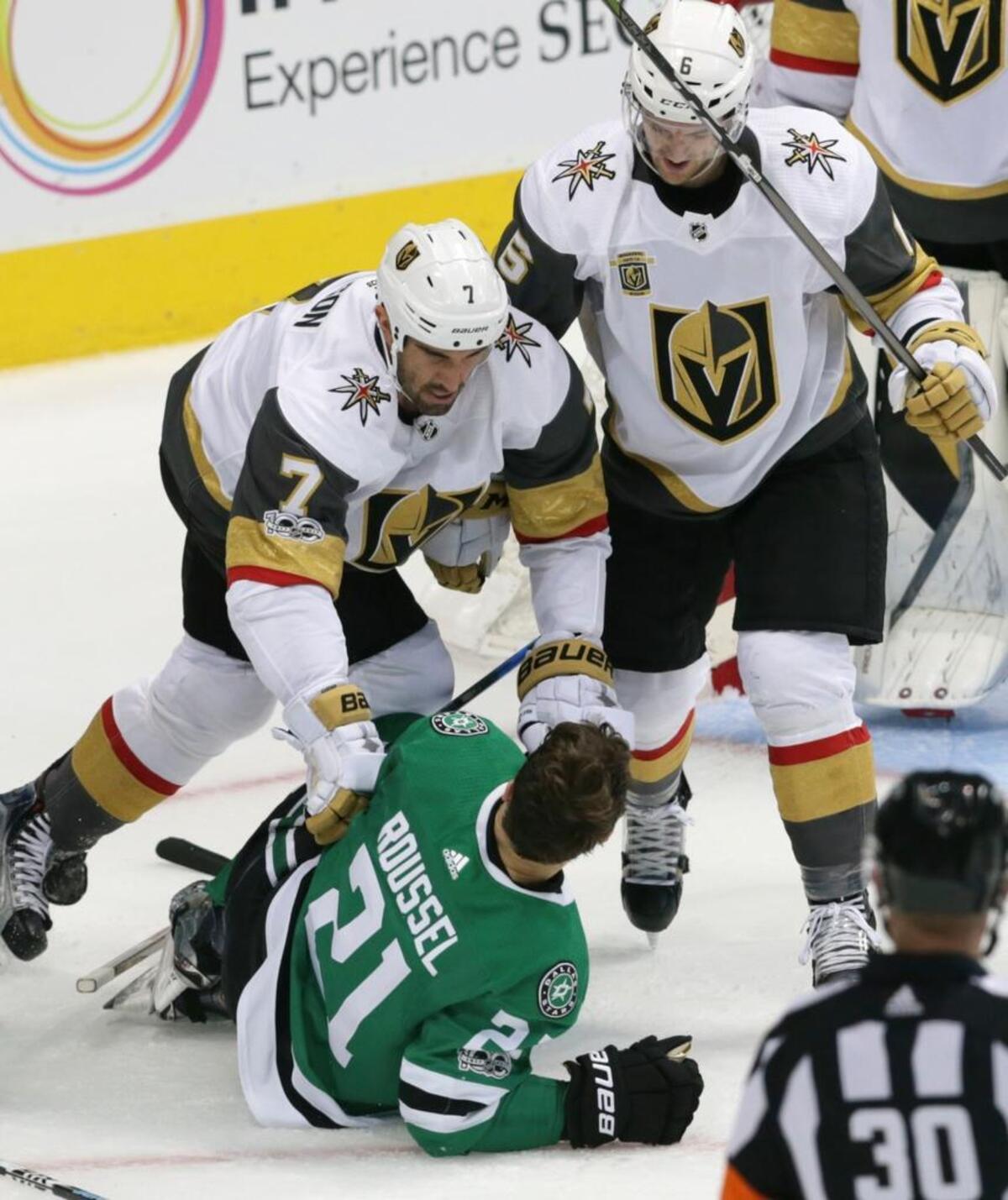 Dallas Stars left wing Antoine Roussel (21) is put on the ice by Vegas Golden Knights defensemen Jason Garrison (7) and Deryk Engelland (5) during the first period of an NHL hockey game in Dallas, Friday, Oct. 6, 2017.