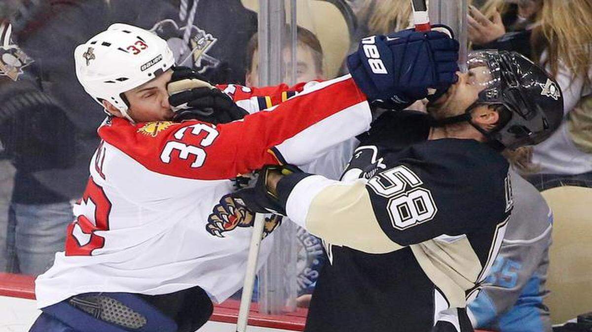 
Pittsburgh Penguins' Kris Letang (58), and Florida Panthers' Willie Mitchell (33) each get a face full of glove during a fight in the first period of an NHL hockey game in Pittsburgh, Saturday, Dec. 20, 2014.
