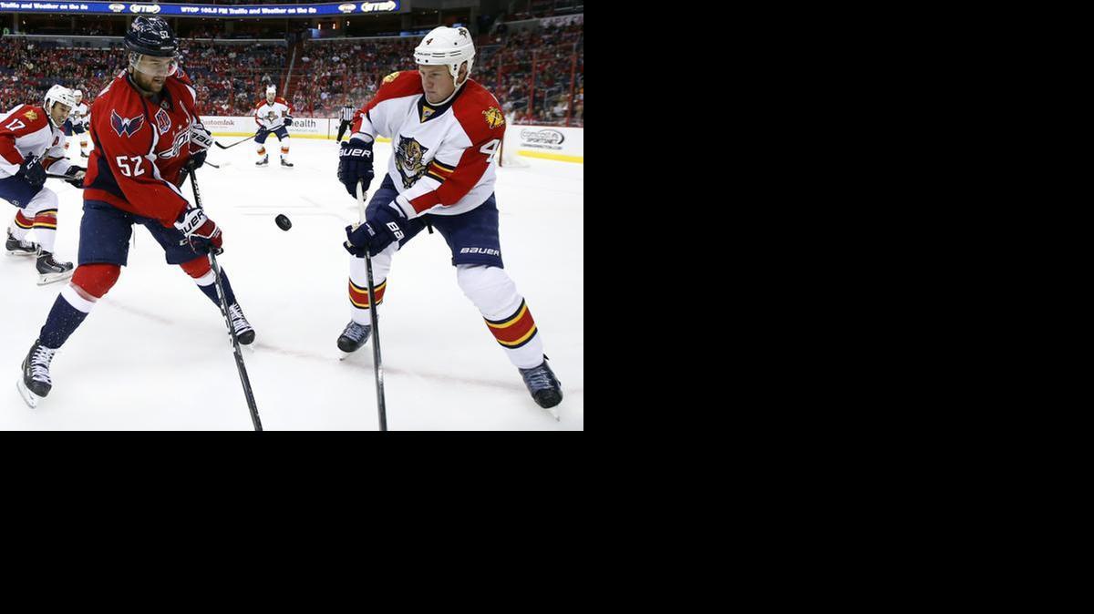 <cutline_leadin>Loose puck:</cutline_leadin> The puck is framed between Capitals defenseman Mike Green (52) and Panther Dylan Olsen (4) during this first period play Saturday.<137>of an NHL hockey game, Saturday, Oct. 18, 2014, in Washington.<137>