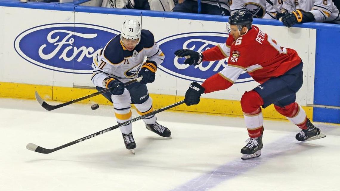 Florida Panthers’ Alexander Petrovic and Buffalo Sabres’ Evan Rodrigues reach for a flying puck in the first period Saturday, April 7, 2018, at the BB&T Center in Sunrise, Fla.