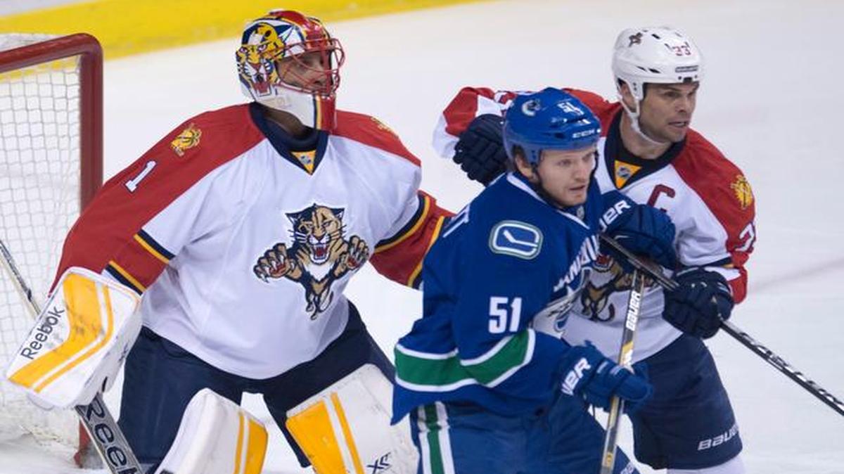 
Florida Panthers goalie Roberto Luongo (1) keeps his eye on the play as Panthers defenseman Willie Mitchell (33) tries to clear Vancouver Canucks right wing Derek Dorsett (51) from in front of the net during first-period NHL hockey game action in Vancouver, British Columbia, Thursday, Jan. 8, 2015.
