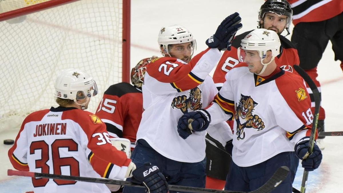 Florida Panthers' Reilly Smith (18) celebrates his goal with Vincent Trocheck (21) and Jussi Jokinen (36), of Finland, as New Jersey Devils' David Schlemko (8) watches during the third period of an NHL hockey game Thursday, Dec. 17, 2015, in Newark, N.J. The Panthers defeated the Devils 5-1.