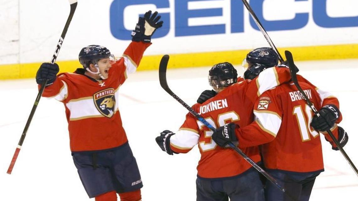 Florida Panthers Jared McCain raises his arms as he approaches teammates hugging Aleksander Barkov who scored the winning goal in overtime as they defeat the New Jersey Devils in the season opener at the BB&T Center in Sunrise, Florida on Thurs., Oct.13, 2016.