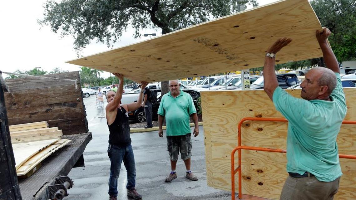 Jose Luis, left, and Miro Espana load plywood into a truck in preparation for Hurricane Matthew on Wednesday.