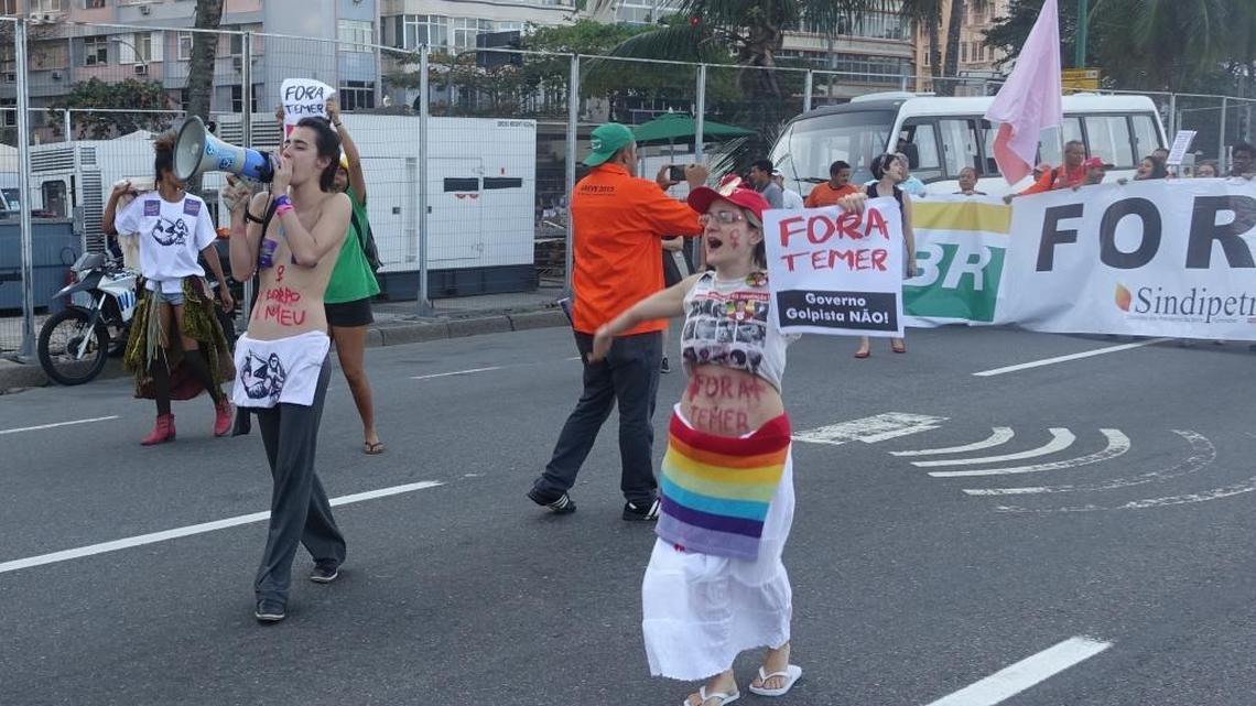 Protesters march at a leisurely pace down a street that runs alongside Copacabana Beach.
