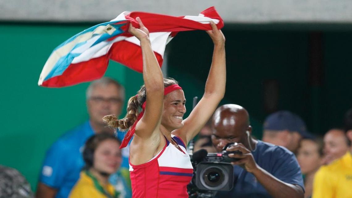 Monica Puig of Puerto Rico celebrates holding her country's flag after winning the gold medal match in the women's tennis competition at the 2016 Summer Olympics in Rio de Janeiro, Brazil, Saturday, Aug. 13, 2016.