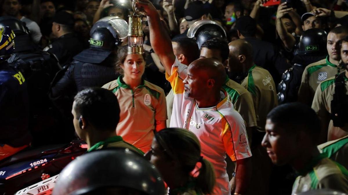 David Vieira Bisbo, a bar owner in the Chapeu Mangueria slum, holds the Olympic flame after his Olympic torch run along the streets of Copacabana, as the torch makes its way to the opening ceremony of the 2016 Summer Olympics in Rio de Janeiro, Brazil, early Fri., Aug. 5, 2016.