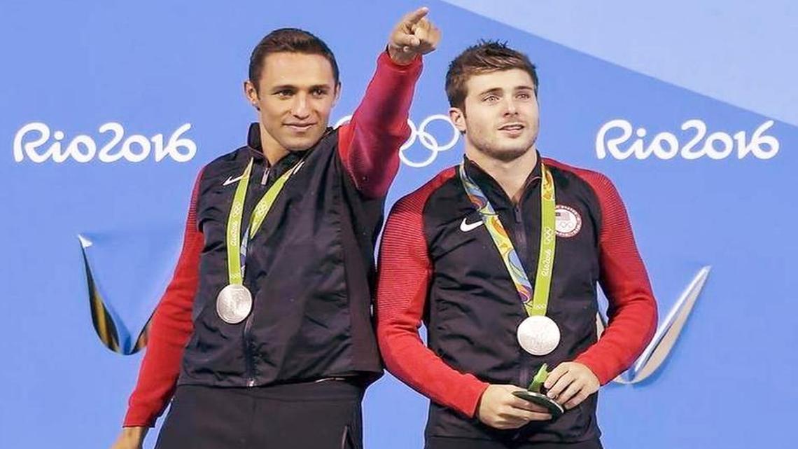 U.S. diver Sam Dorman, left, from the University of Miami, points to the crowd as he and Michael Hixon celebrate after winning the silver medal in the men’s 3-meter synchronized diving event at the Summer Olympics in Rio de Janeiro. Their clutch final dive brought them the medal.