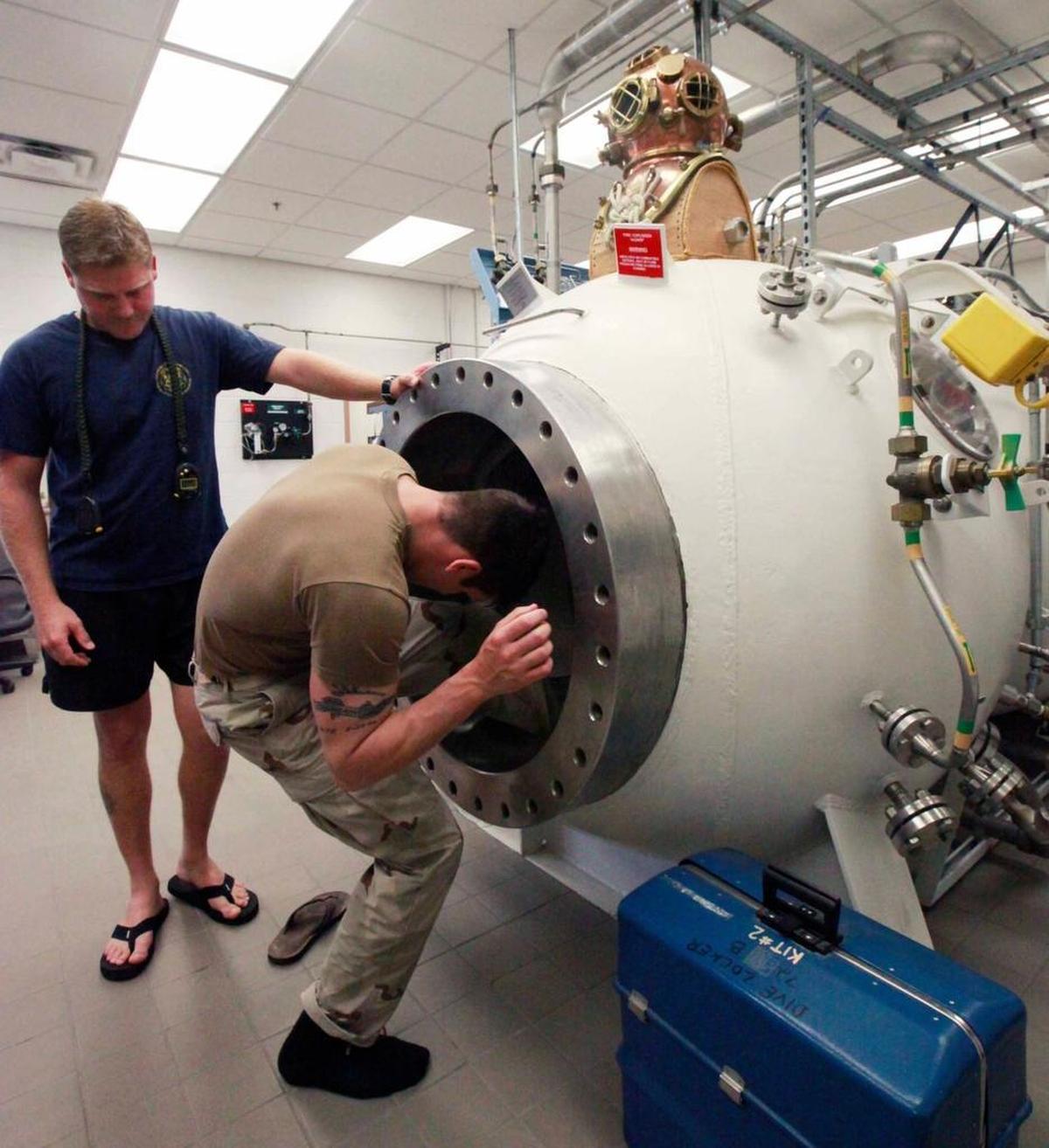 Navy Seaman Christopher Lamonica of Hyde Park, N.Y., exits a pressure chamber on March 30, 2009, at the Dive Locker at the U.S. Navy base at Guantánamo Bay, Cuba. Navy Petty Officer 1st Class Brent Roberts of Cove, Ark., who supervised the mock dive, watches from left. The test checked Lamonica’s ability to clear his ears under pressure as a prerequisite to Navy SEAL training.