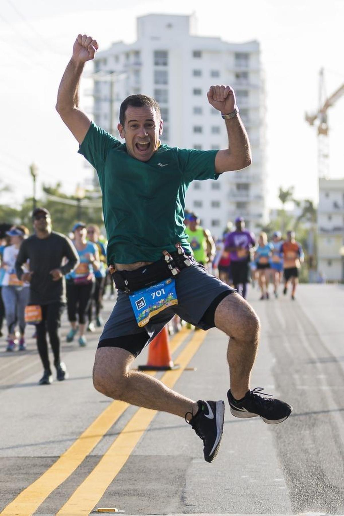 A runner jumps with joy as he makes his way along Venetian Way during the Miami Marathon & Half Marathon on Sunday, Jan. 28, 2018.