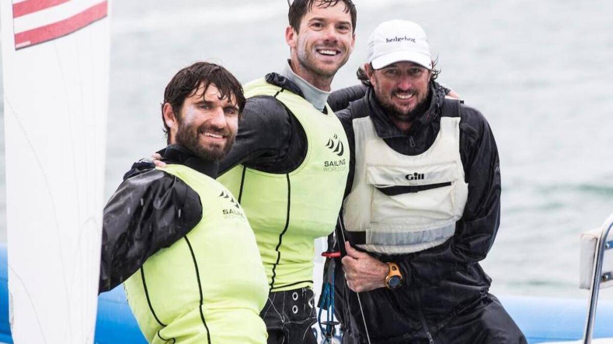 From left, Stu McNay, Dave Hughes of Coconut Grove and coach Nathan Wilmot celebrate 470 class gold medal at Sailing World Cup Miami on Sunday.