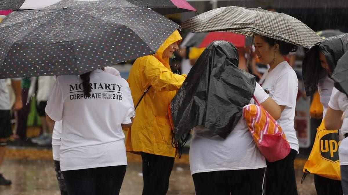 
Runners stand under umbrellas as a woman hands out bags at the 30th anniversary of the Mercedes-Benz Miami Corporate Run. 27,600 people registered for this 3.1-mile run that begins and ends on Biscayne Boulevard next to Bayfront Park on Thursday, April 23, 2015.
