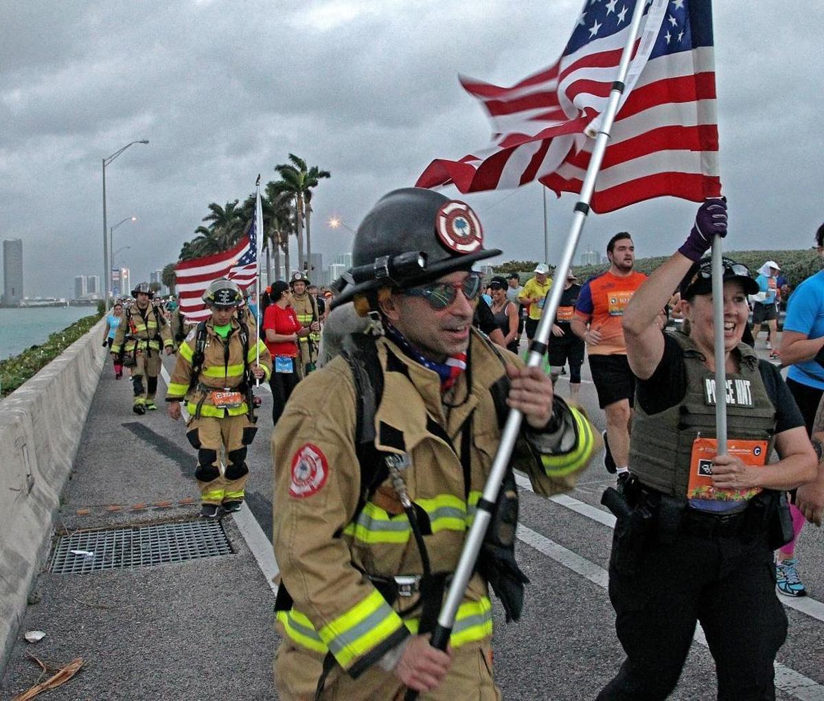 City of Miami firefighter Giovanni Venturino and Miami Beach police officer Traci Sierra walk with American flags as the group of first responders — Miami and Miami Beach police officers and firefighters — crossed the MacArthur Causeway to bring attention to first responders battling PTSD. The group walked to honor the death of one their own as they participated in the Miami Marathon and Half Marathon on Sunday, Jan. 28, 2018.