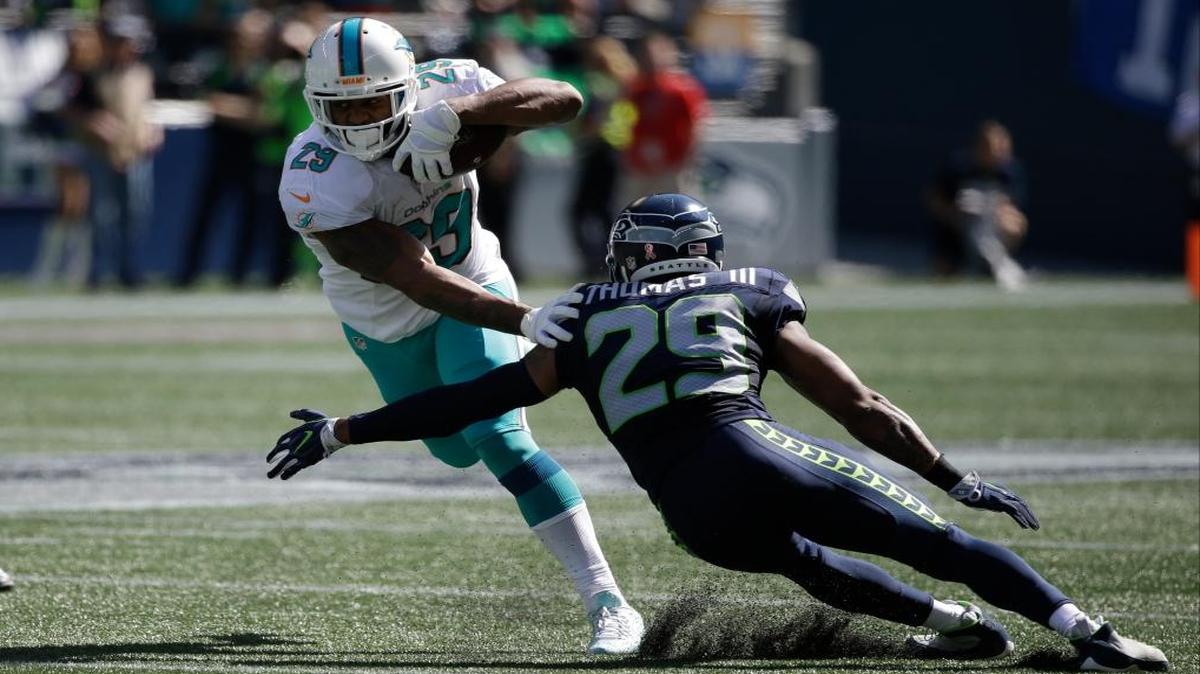 Miami Dolphins running back Arian Foster left, runs against Seattle Seahawks free safety Earl Thomas, right, in the first half of an NFL football game, Sun., Sept. 11, 2016, in Seattle.