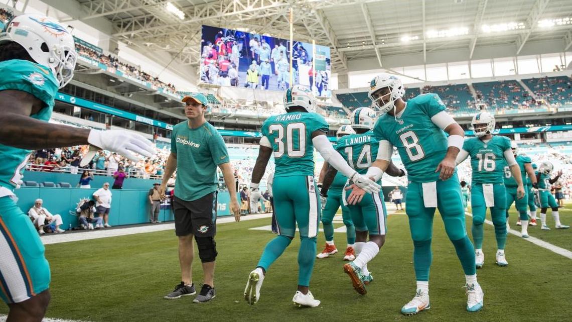 Miami Dolphins quarterbacks Ryan Tannehill (left) and Matt Moore (8) welcome the team onto the field before the start of the game at Hard Rock Stadium in Miami Gardens, Florida, Jan. 1, 2017.