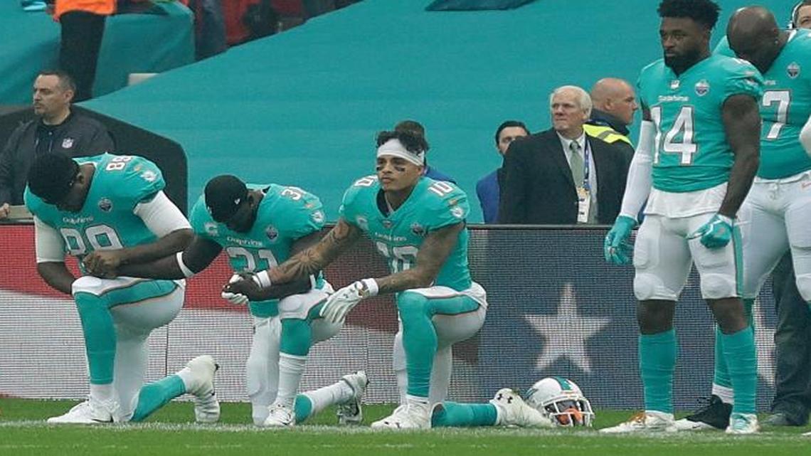 Miami Dolphins' Julius Thomas (89), Michael Thomas (31) and Kenny Stills take a knee as the U.S. national anthem is played before an NFL football game against the New Orleans Saints at Wembley Stadium in London, Sunday Oct. 1, 2017.