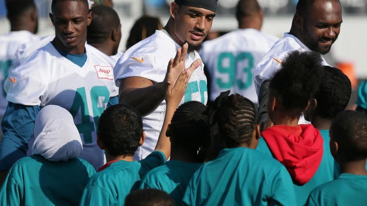 
Miami Dolphins defensive end Olivier Vernon, center, high-fives schoolchildren as they meet after practice in Allianz Park in London on Friday, Oct. 2, 2015.
