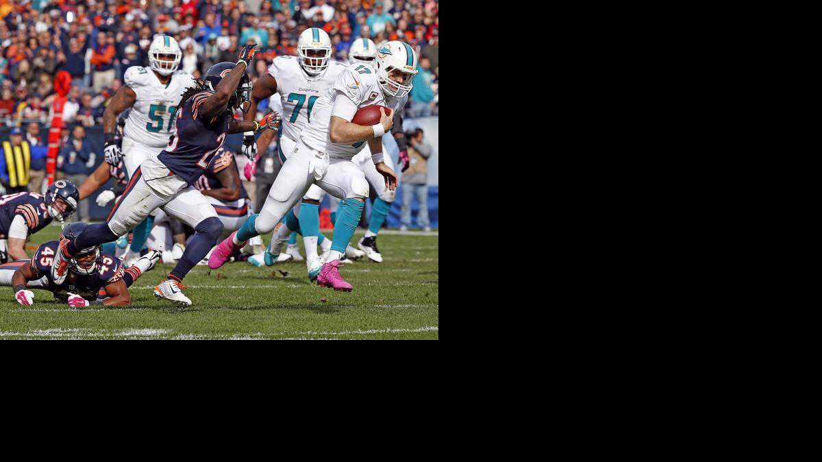 
Miami Dolphins quarterback Ryan Tannehill runs for yardage in the third quarter to help set up a touchdown as Chicago Bears defensive back Tim Jennings chases him at Soldier Field in Chicago, Illinois, on Sunday, Oct. 19, 2014.
