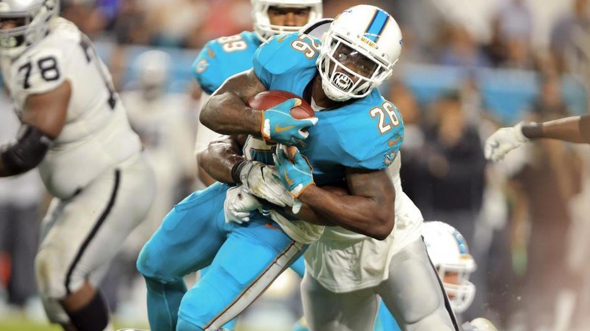 Running back Damien Williams fights with two Raiders defenders for extra yards in the second quarter Sunday.