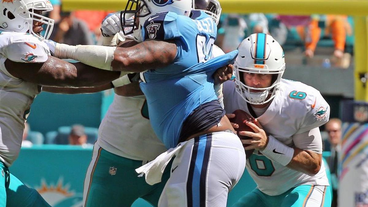 Miami Dolphins quarterback Jay Cutler ducks down behind linemen as he looks for a receiver Sunday against the Tennessee Titans.
