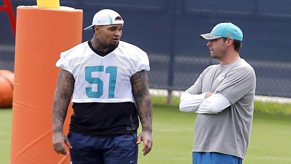 Injured center Mike Pouncey talks with coach Adam Gase during practice at the Miami Dolphins facility in Davie last season.
