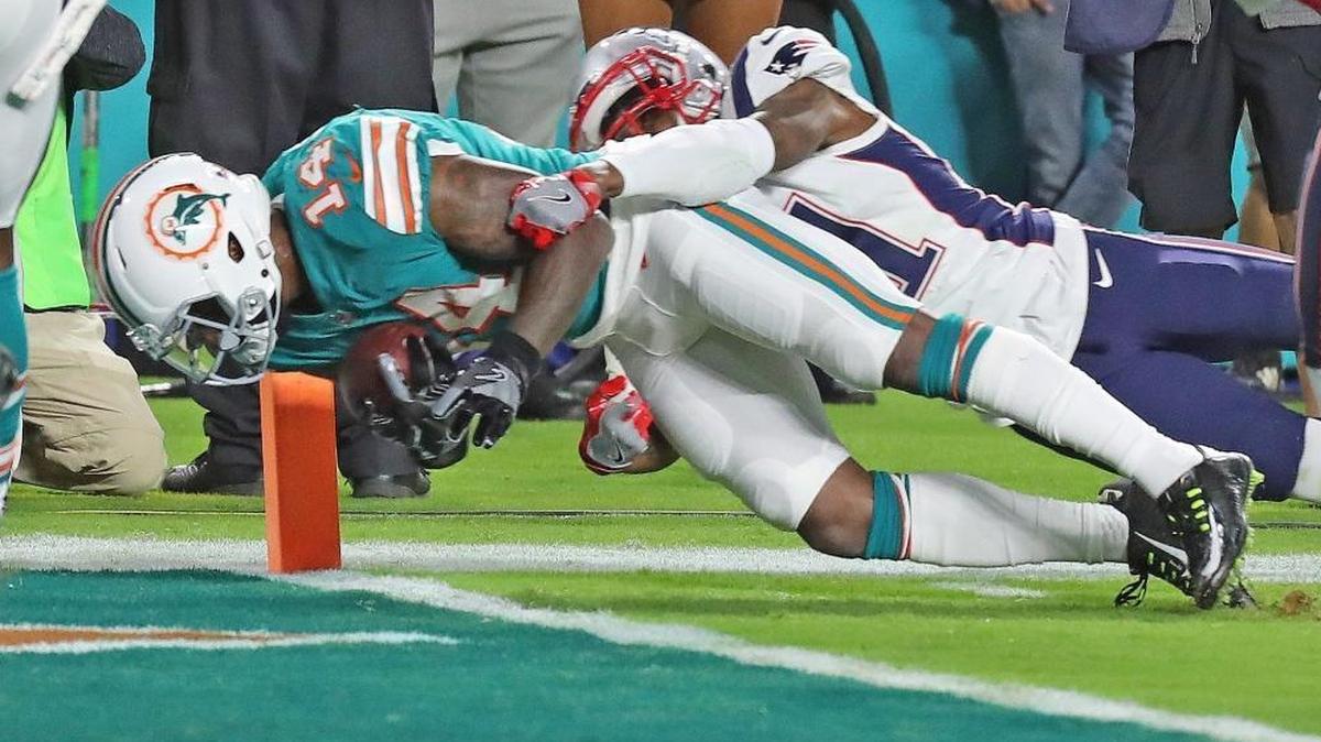 Miami Dolphins’ Jarvis Landry (14) scores a second quarter touchdown as the New England Patriots’ Jonathan Jones (31) tries to tackle him at Hard Rock Stadium in Miami Gardens, Florida, Dec. 11, 2017.