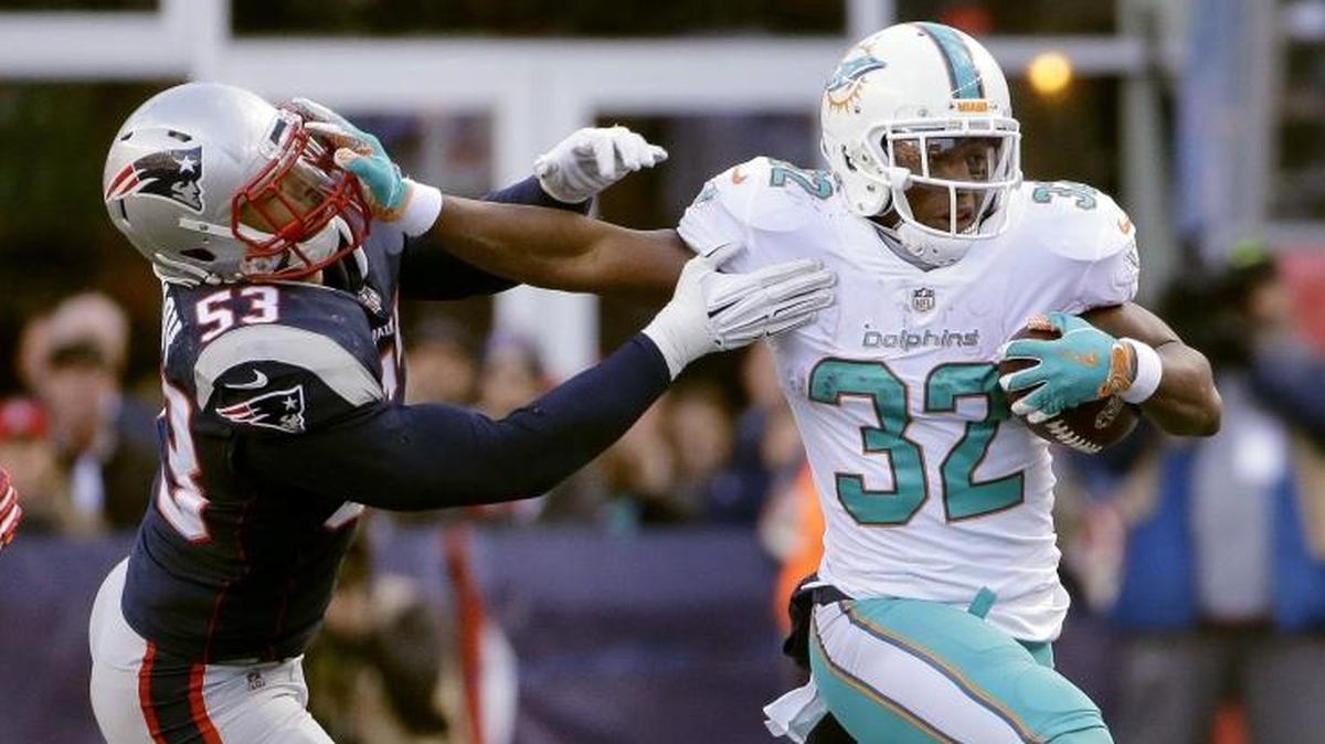Miami Dolphins running back Kenyan Drake (32) gives a stiff arm to New England Patriots linebacker Kyle Van Noy (53) during the first half of last Sunday’s game. (AP Photo/Steven Senne)
