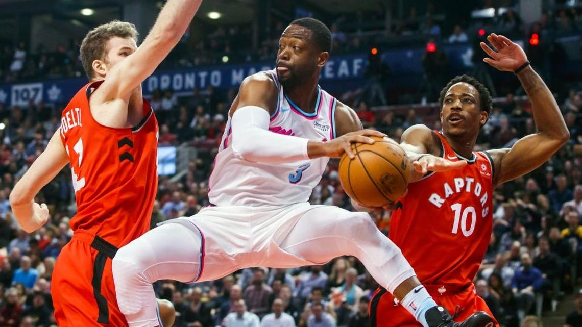 Miami Heat Dwyane Wade passes the ball against Toronto Raptors Jakob Poeltl, left, and DeMar DeRozan during Tuesday’s game. (Mark Blinch/The Canadian Press via AP)