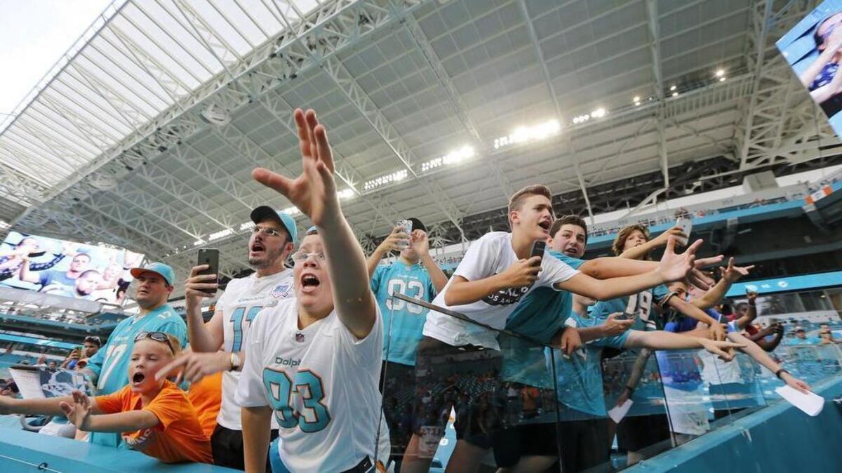Fans scream for players for a football after pregame warmups as the Miami Dolphins host the Tennessee Titans at Hard Rock Stadium on Thurs., Sept. 1, 2016.