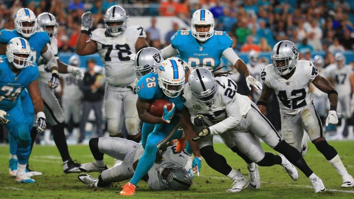 Running back Damien Williams #26 of the Miami Dolphins is tackled by free safety Reggie Nelson #27 of the Oakland Raiders at Hard Rock Stadium on Nov. 5, 2017 in Miami Gardens, Florida.