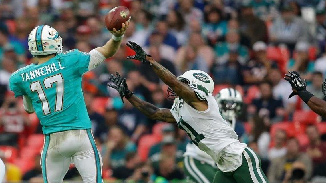 Miami Dolphins' Ryan Tannehill, left, tries to get a pass away under pressure during the NFL football game between the New York Jets and the Miami Dolphins and at Wembley stadium in London, Sun., Oct. 4, 2015.
