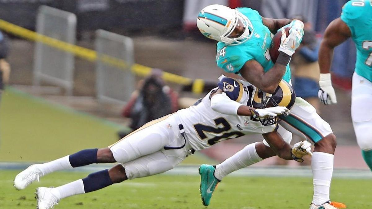 Miami Dolphins Jarvis Landry is tackled after a reception by Los Angeles Rams mark Barron in the first quarter at the Los Angeles Memorial Coliseum in Los Angeles, California, Nov. 20, 2016.
