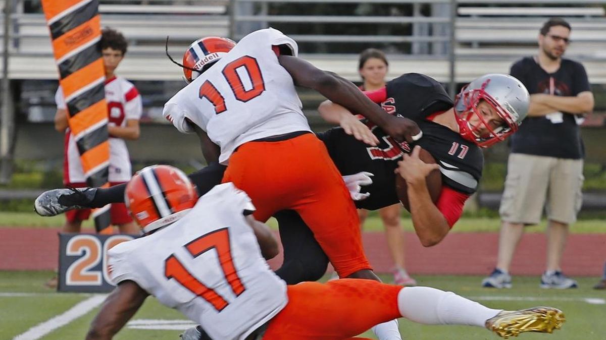 Four-star Carol City linebacker De’Andre Wilder (10) sacks Gables quarterback Nick Galuppo, left on Thurs., Aug. 25, 2016.