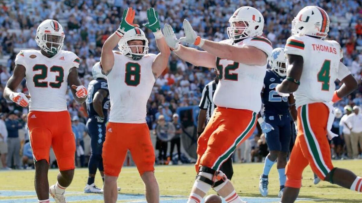 Miami's Braxton Berrios (8) celebrates his touchdown with Christopher Herndon IV (23), KC McDermott (52) and Jeff Thomas (4) during the second half of an NCAA college football game against North Carolina in Chapel Hill, N.C., Saturday, Oct. 28, 2017. Miami won 24-19.