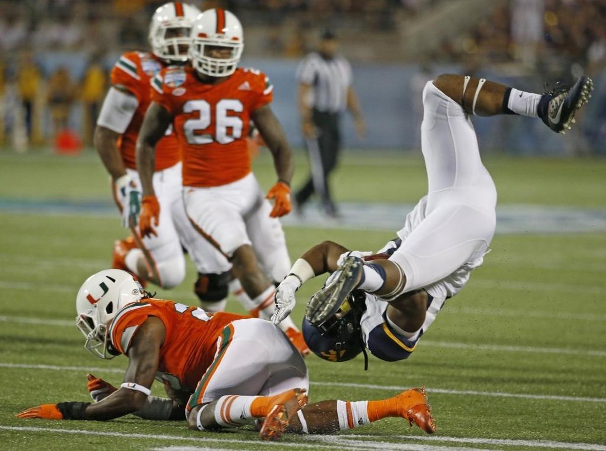 Miami Hurricanes defensive back Adrian Colbert (25) up ends West Virginia Mountaineers running back Martell Pettaway (32) on a hit in the fourth quarter as the University of Miami takes on the West Virginia Mountaineers at the Russell Athletic Bowl in Orlando Wed., Dec. 28, 2016.