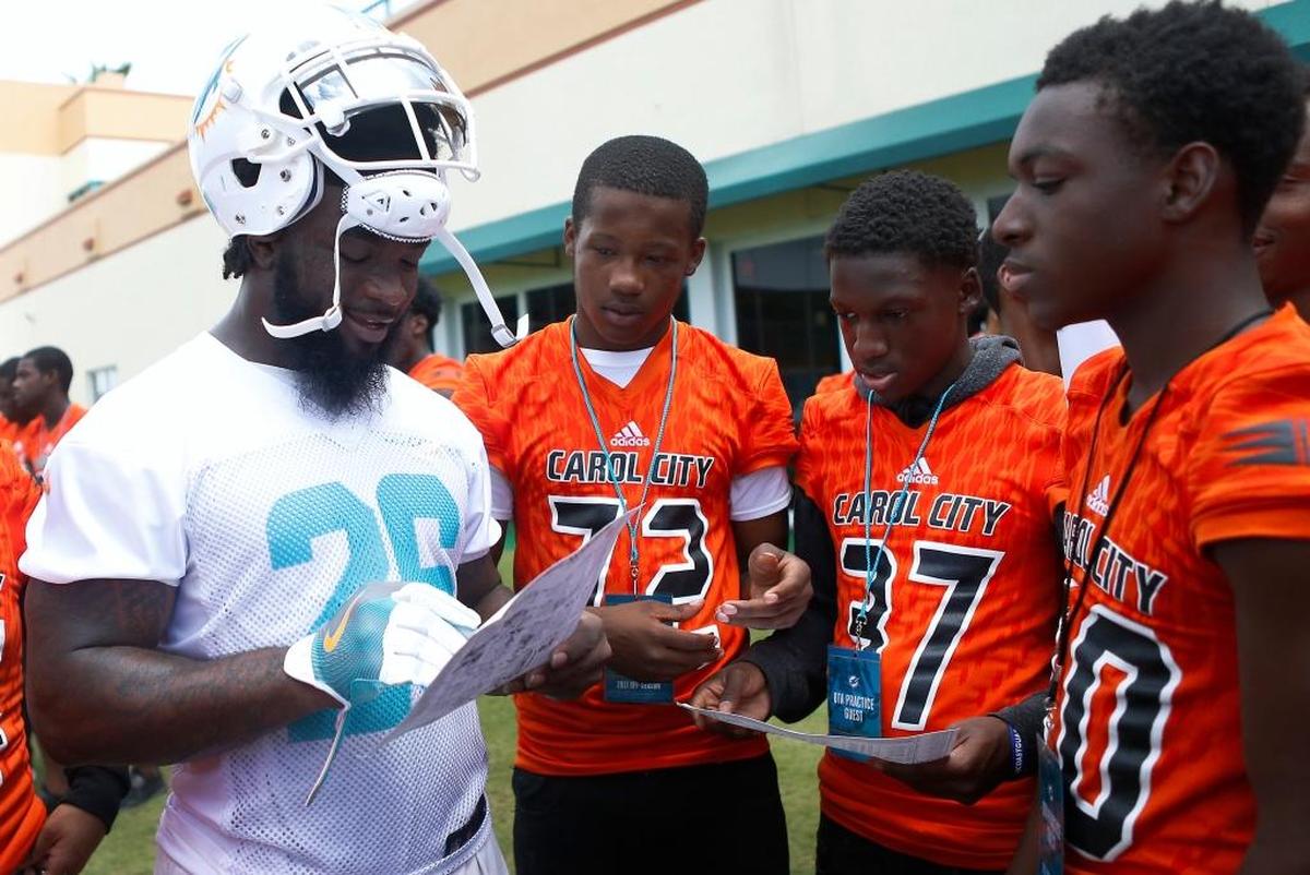 Miami Dolphins running back Damien Williams signs autographs to Miami Carol City Senior High School students after the NFL football minicamp, Thursday, June 15, 2017, at the team's training facility in Davie.