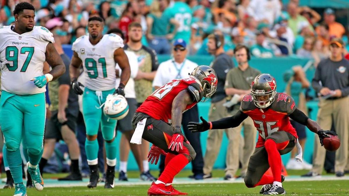 Miami Dolphins Jordan Phillips (97) and Cameron Wake (91) watch Tampa Bay Buccaneers Kwon Alexander (58) Robert McClain (36) celebrate after a McClain interception at Hard Rock Stadium in Miami Gardens, Florida, Nov. 19, 2017.