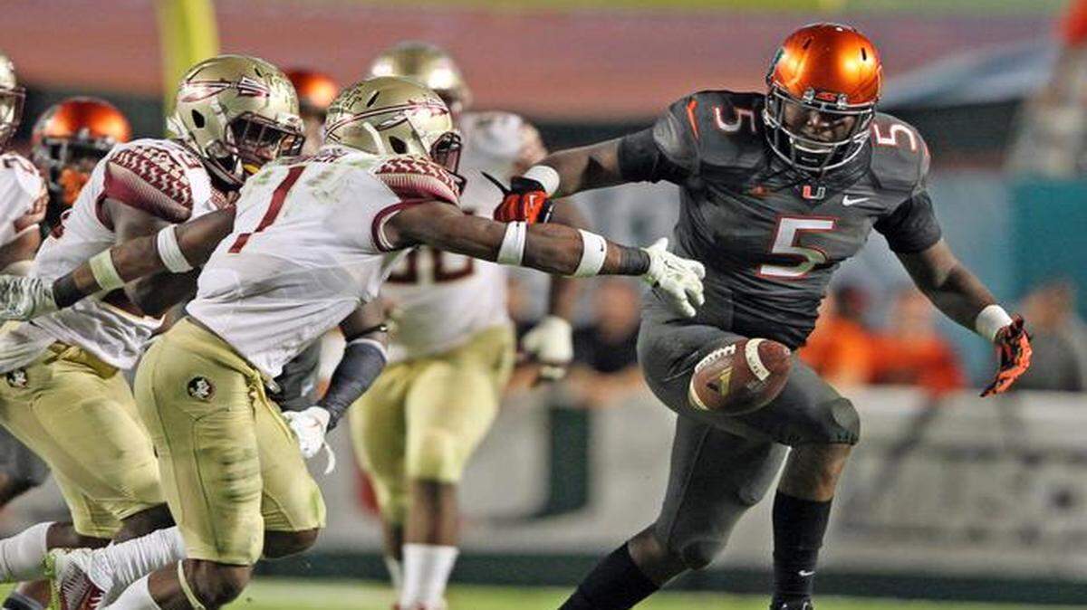 
UM’s Jermaine Grace gets the ball stripped by FSU’s Tyler Hunter in the third quarter at Sun Life Stadium in Miami Gardens, November 15, 2014.
