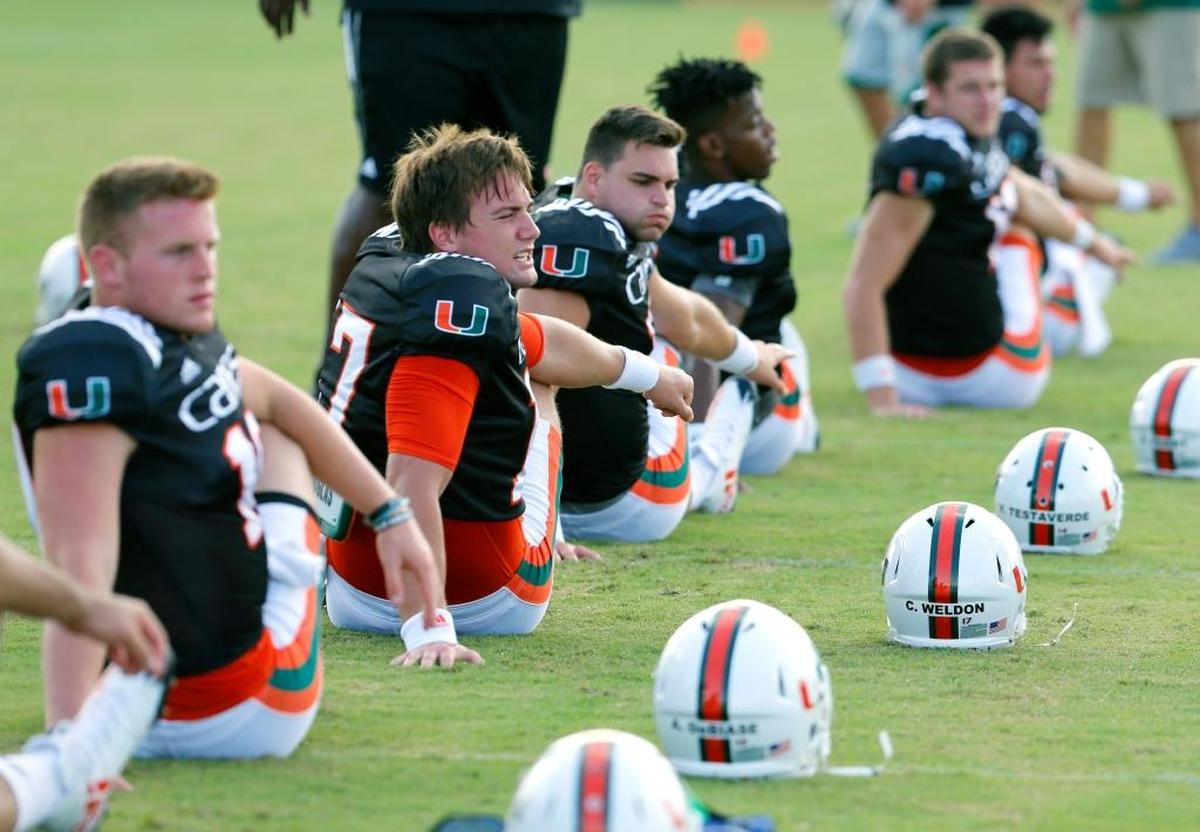 UM quarterbacks, including Cade Weldon (17) stretch during warmups on the third day of University of Miami football camp at Greentree Field on Thursday, August 3, 2017.