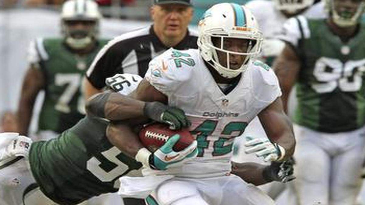 
Dolphins tight end Charles Clay is tackled by the Jets’ Demario Davis after a catch at Sun Life Stadium on Dec. 29, 2013.
