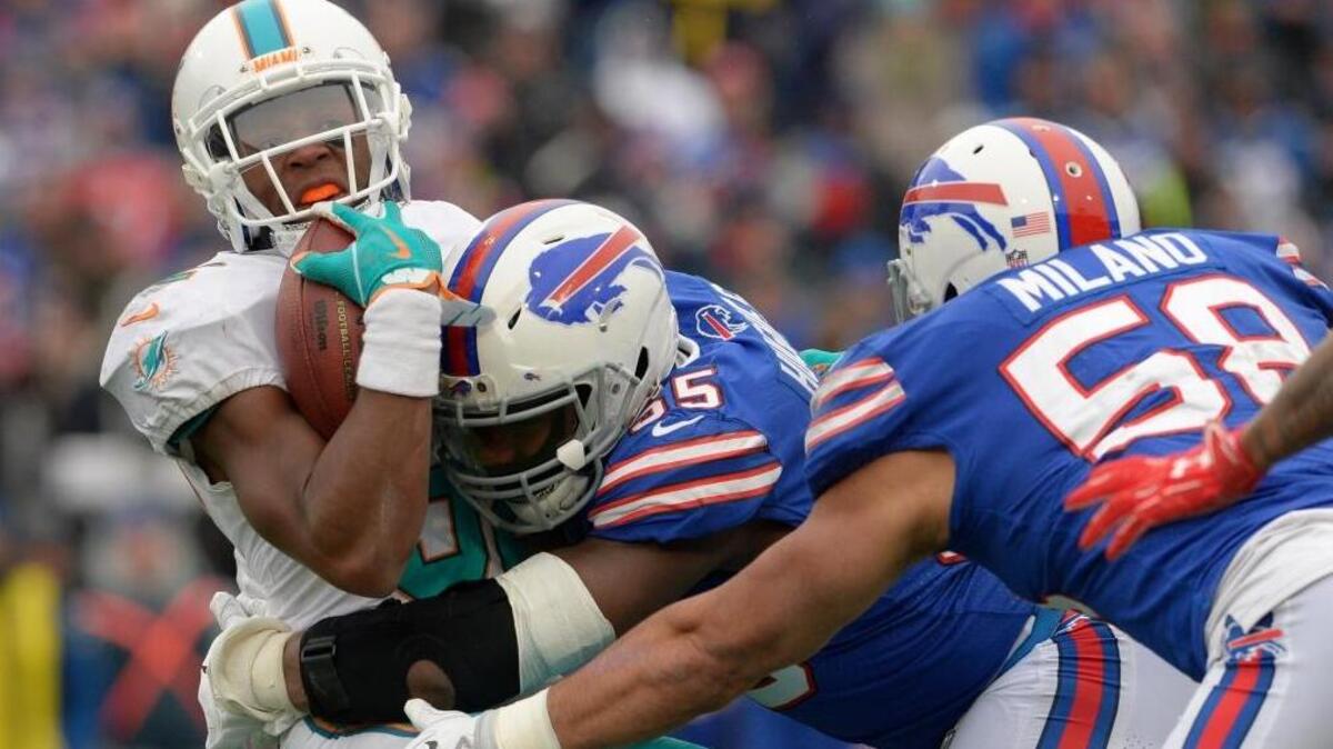 Buffalo Bills' Jerry Hughes (55) and Matt Milano (58) tackle Miami Dolphins' Kenyan Drake (32) during the first half of an NFL football game Sun., Dec. 17, 2017, in Orchard Park, N.Y.